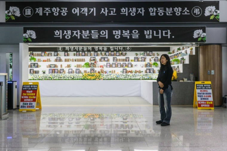 Lee Hyo-eun devant un autel commémoratif dédié aux victimes du crash du vol 2216 de Jeju Air en décembre 2024, dans le hall des arrivées de l'aéroport international de Muan, le 14 décembre 2025 en Corée du Sud ( AFP / ANTHONY WALLACE )