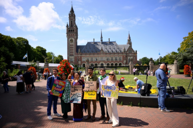 Vishal Prasad (3e à D), directeur de la campagne Pacific Island Students Fighting Climate Change, pose avec d'autres militants devant la Cour internationale de justice (CIJ) à La Haye, le 23 juillet 2025 ( AFP / JOHN THYS )