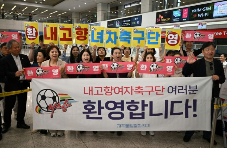 Des supporters sud-coréens brandissant des banderoles pour accueillir les footballeuses du club nord-coréen de Naegohyang, à l'aéroport international d'Incheon, le 17 mai 2026 ( AFP / Jung Yeon-je )
