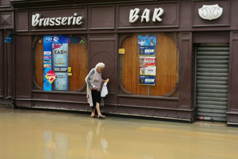 Une passante dans une rue inondée de Coulommiers (Seine-et-Marne), à l'est de Paris, le 10 octobre 2024 ( AFP / Dimitar DILKOFF )