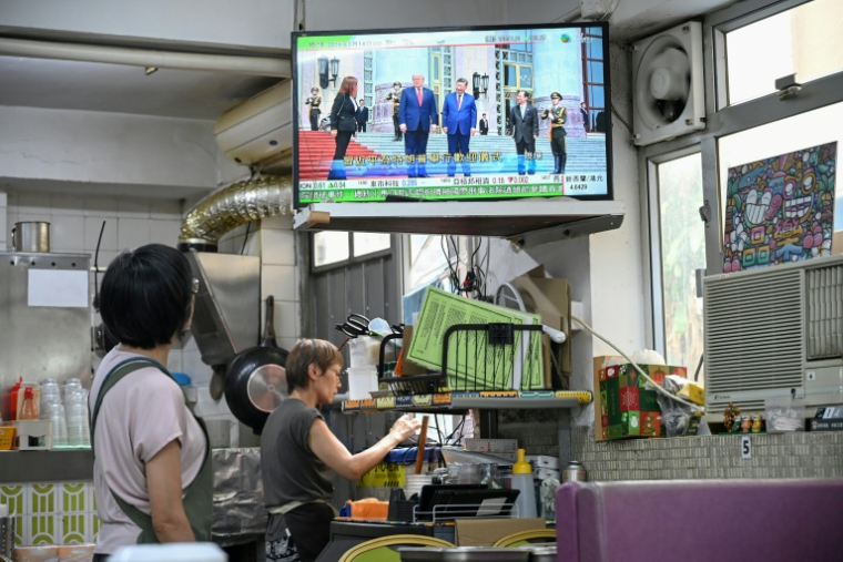 Un écran dans un restaurant de Hong Kong diffuse en direct la visite de Donald Trump en Chine, le 14 mai 2026 ( AFP / Peter PARKS )