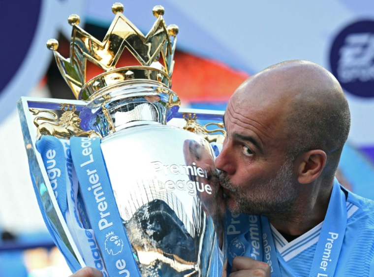 Pep Guardiola embrasse le trophée de la Premier League, le 19 mai 2024 à l'Etihad Stadium ( AFP / Oli SCARFF )