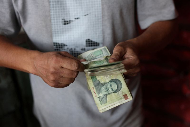 Un commerçant tient des rials iraniens dans un marché local de Téhéran