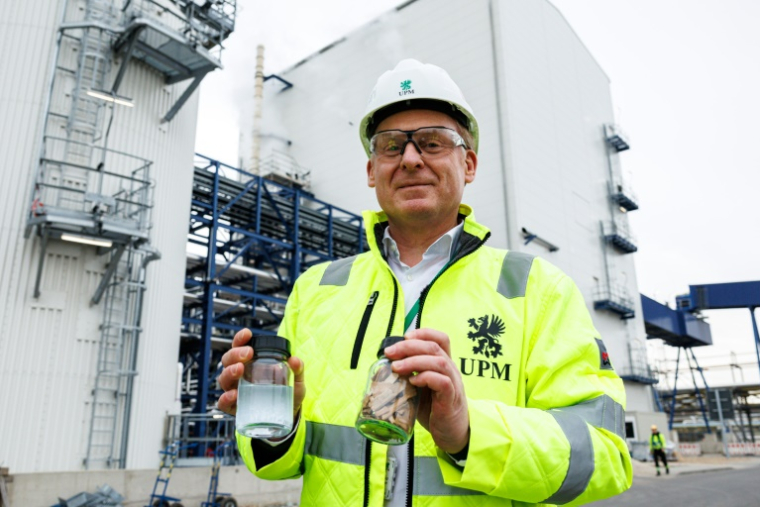 Harald Dialer, vice-président exécutif Technologie d'UPM Biorefining & Technology, présente un bocal contenant des copeaux de bois de hêtre et un autre contenant le produit final, la monoéthylène glycoline, devant les installations chimiques d'UPM Biorefining & Technology dans le parc chimique de Leuna, le 14 novembre 2025 ( AFP / JENS SCHLUETER )