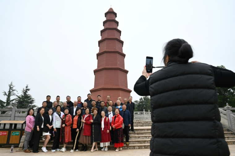 Des visiteurs posent pour une photo devant la pagode rouge, à l'extérieur du Centre culturel du tabac à Yuxi, dans la province du Yunnan, le 31 mars 2025 dans le sud-ouest de la Chine ( AFP / GREG BAKER )
