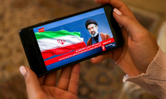 Une femme consulte sur son mobile un message du guide suprême iranien Mojtaba Khamenei, le 26 mai 2026 à Téhéran ( AFP / ATTA KENARE )