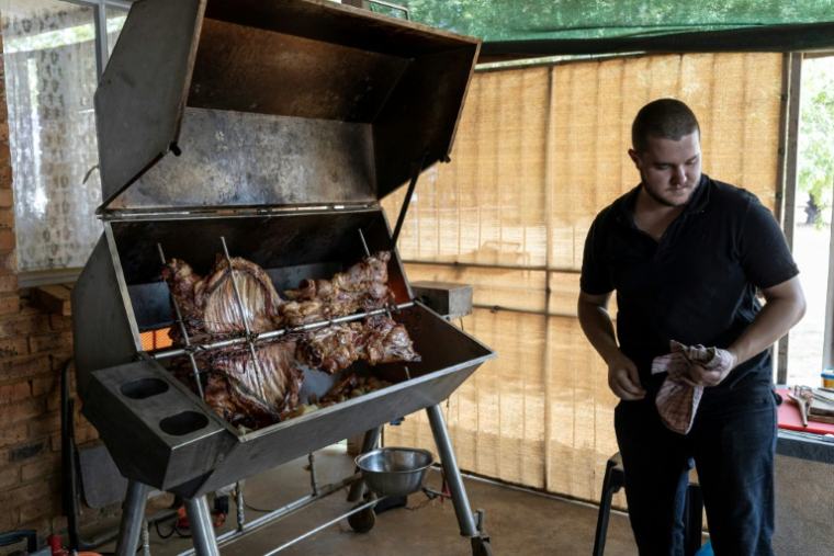 Driaan Beyers prépare un agneau à la broche à Kleinfontein, en Afrique du Sud, le 13 septembre 2025 ( AFP / Wikus de Wet )