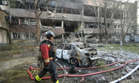 Un pompier devant une voiture calciné et un immeuble endommagé après une frappe de drone russe à Kharkiv, le 11 juin 2025 en Ukraine ( AFP / SERGEY BOBOK )