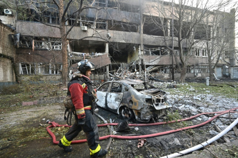 Un pompier devant une voiture calciné et un immeuble endommagé après une frappe de drone russe à Kharkiv, le 11 juin 2025 en Ukraine ( AFP / SERGEY BOBOK )