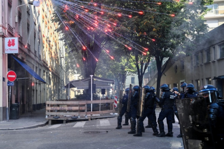 Des policiers anti-émeutes sont rassemblés alors que des feux d'artifice éclatent au-dessus d'eux, lors d'une manifestation de lycéens aux côtés d'un syndicat d'enseignants à Lyon, dans le Rhône, le 6 octobre 2026 ( AFP / OLIVIER CHASSIGNOLE )