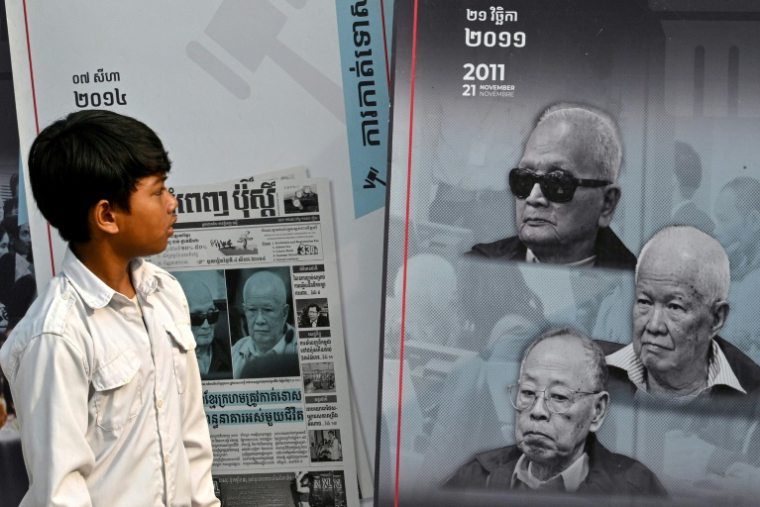 Un jeune Cambodgien regarde une affiche avec les photos des anciens hauts dirigeants khmers rouges dans le cadre d'un programme sur le génocide, dans une école de la provoince de Banteay Meanchey, le 24 mars 2025 ( AFP / TANG CHHIN Sothy )