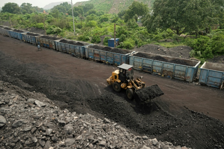 Un ouvrier transporte des tas de charbon brut dans des wagons de train, extraits d'une mine à ciel ouvert à la périphérie de Dhanbad, dans l'État indien du Jharkhand, le 13 août 2025 ( AFP / Vishal kumar singh )