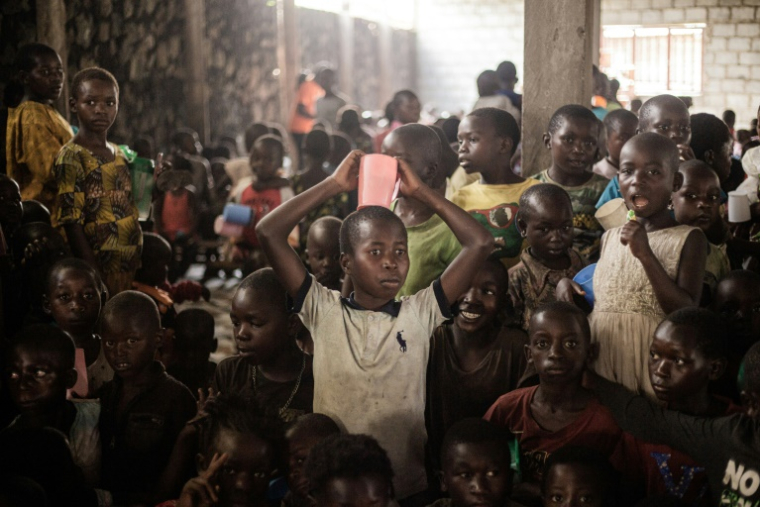 Des enfants attendent une distribution de produits alimentaires dans le camp de personnes déplacées de Buhimba, le 22 décembre 2024 en RDC ( AFP / Jospin Mwisha )