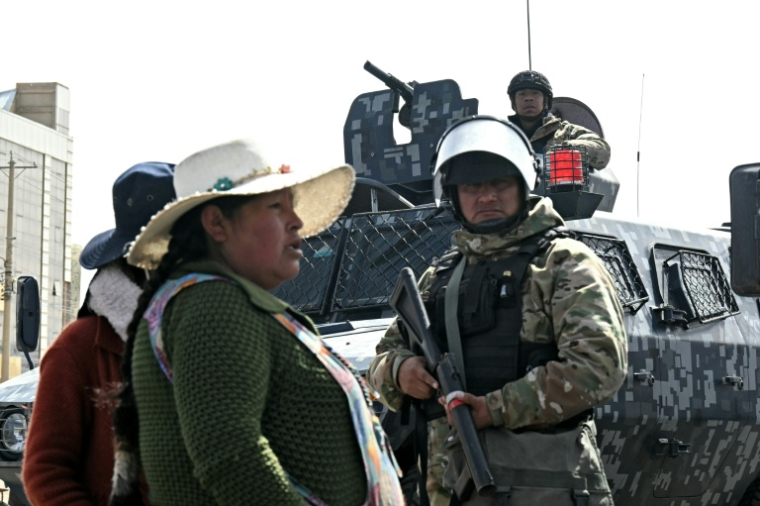 Des habitants passent près de policiers militaires dans une zone de blocage à El Alto, en Bolivie, le 20 juin 2026 ( AFP / AIZAR RALDES )