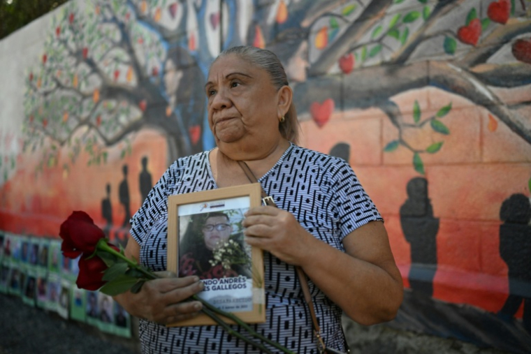 Sandra Gallegos tient un portrait de son fils disparu, Fernando Rosales, lors de l'inauguration d'une fresque murale en hommage aux personnes disparues, à l'Université d'El Salvador, à San Salvador, le 19 mars 2026 ( AFP / STRINGER )