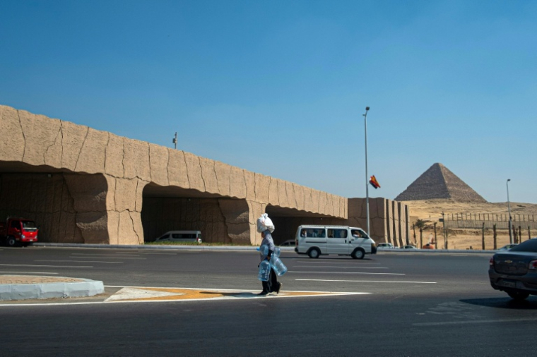 Une femme marche le long d'une route surélevée reliant les pyramides de Guizeh au Grand musée égyptien (GEM) du Caire, le 18 September 18 2025, avant son ouverture officielle ( AFP / Khaled DESOUKI )