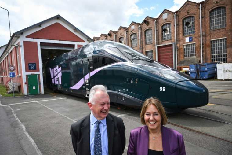 Rachel Picard (D) et Timothy Jackson, cofondateurs de la compagnie ferroviaire privée française Velvet, posent devant l'une des locomotives de leur entreprise à l'usine Alstom de Belfort, dans l'est de la France, le 27 juin 2025 ( AFP / SEBASTIEN BOZON )