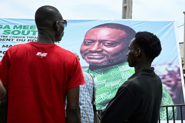 Des partisans du parti d'opposition ivoirien PDCI se tiennent devant une affiche de leur candidat Tidjane Thiam lors d'un meeting à Abidjan, le 3 mai 2025. ( AFP / Issouf SANOGO )