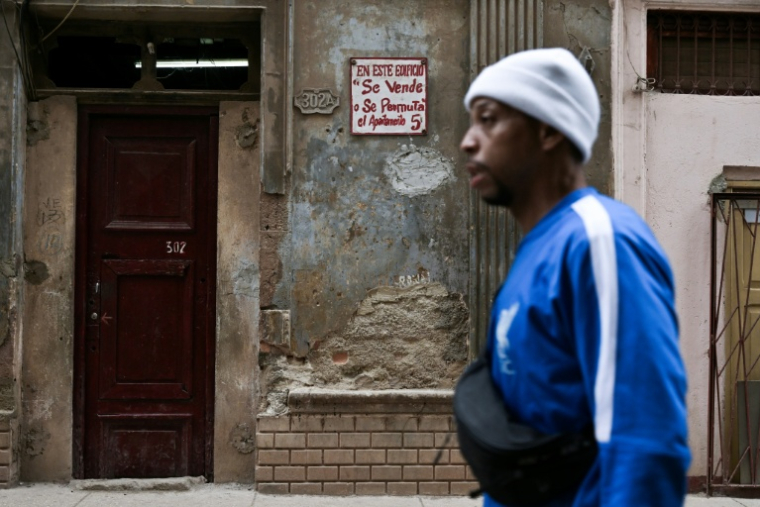 Un homme marche devant un immeuble où un appartement est en vente dans un quartier historique de La Havane, le 23 avril 2026 ( AFP / YAMIL LAGE )