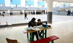 Une femme, assise à côté d'un enfant, supervise ses études en ligne sur un téléphone portable dans une école publique transformée en refuge pour personnes déplacées, à Dekwaneh, au nord de Beyrouth, le 25 mars 2026 au Liban ( AFP / Anwar AMRO )