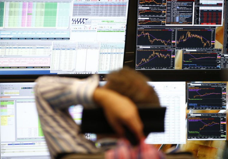 Un trader est assis devant les écrans d'ordinateur à son bureau à la bourse de Francfort