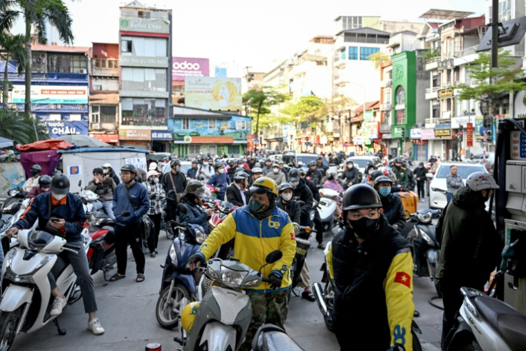 Des motocyclistes font la queue pour faire le plein d'essence dans une station-service à Hanoï, le 10 mars 2026 au Vietnam ( AFP / Nhac NGUYEN )