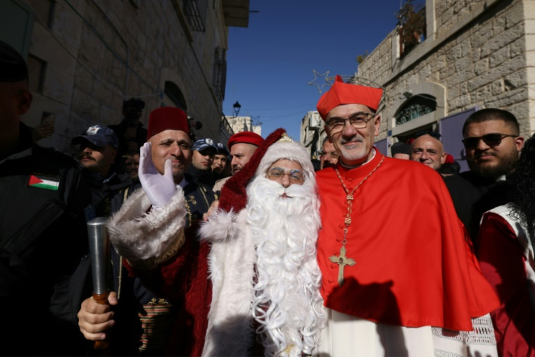 Le patriarche latin de Jérusalem, le cardinal Pierbattista Pizzaballa, pose pour une photo avec un homme habillé en Père Noël avant son arrivée à l'église de la Nativité, à Bethléem, en Cisjordanie occupée, le 24 décembre 2024 ( AFP / HAZEM BADER )