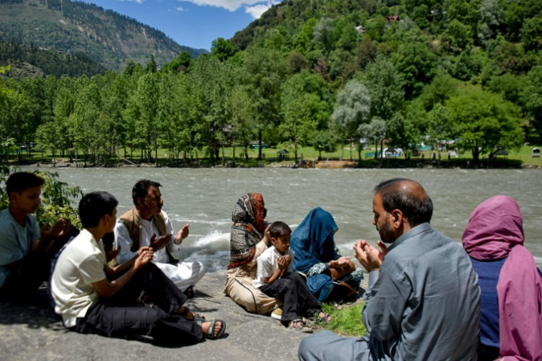 Membres de la famille de Raja Liaqat, décédé le mois dernier dans le village de Keran du côté du Cachemire indien, assis sur les rives de la rivière Neelum sur la rive du Cachemire pakistanais, le 29 mai 2026 ( AFP / Sajjad QAYYUM )