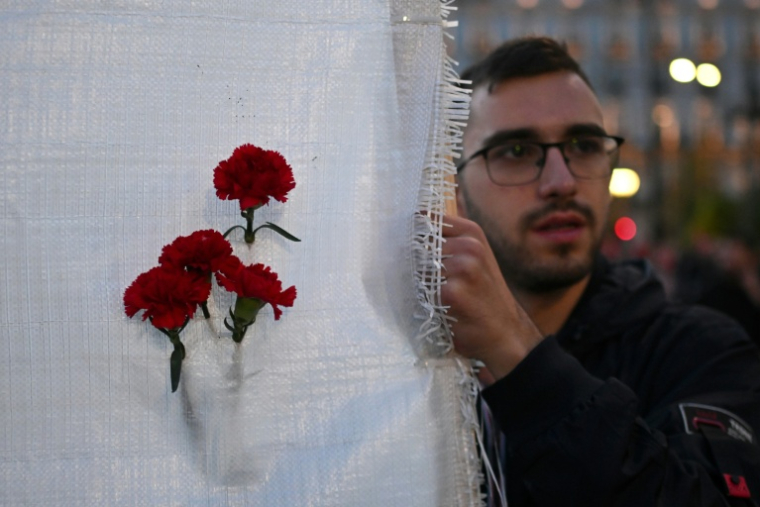 Un manifestant tient une bannière avec des oeillets rouges lors de la marche annuelle commémorant le soulèvement étudiant de 1973 contre la junte, à Athènes, le 17 novembre 2025 ( AFP / Aris MESSINIS )