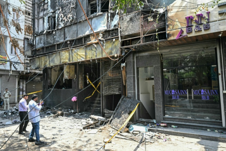 Des enquêteurs sur les lieux après un incendie qui a fait au moins 21 morts dans un hôtel bon marché de New Delhi le 3 juin 2026 ( AFP / Arun SANKAR )
