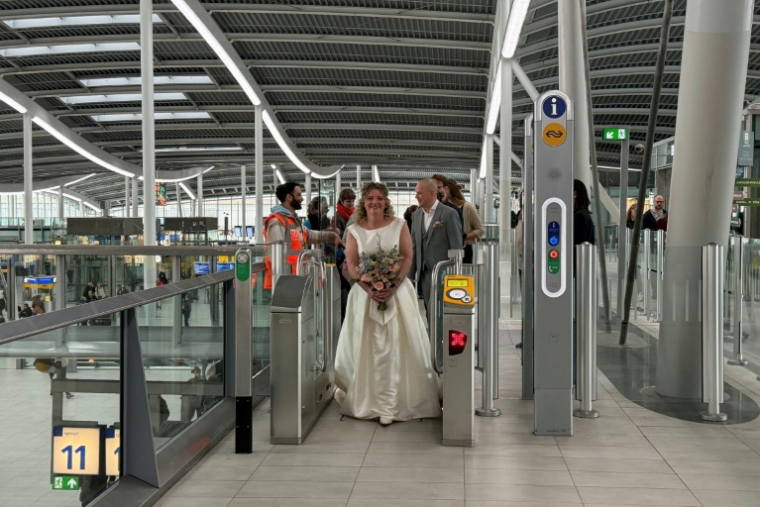 Lara Beters, communicante en développement durable, et son futur époux Mathijs Dordrecht franchissent un portillon pour se rendre à leur mariage dans la gare d'Utrecht, le 2 avril 2026 aux Pays-Bas ( AFP / Stéphanie HAMEL )