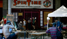 Des personnes récemment expulsées d'un centre social à Rome sont installées devant ses grilles fermées, le 11 août 2026 ( AFP / Filippo MONTEFORTE )