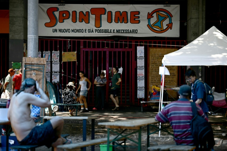 Des personnes récemment expulsées d'un centre social à Rome sont installées devant ses grilles fermées, le 11 août 2026 ( AFP / Filippo MONTEFORTE )