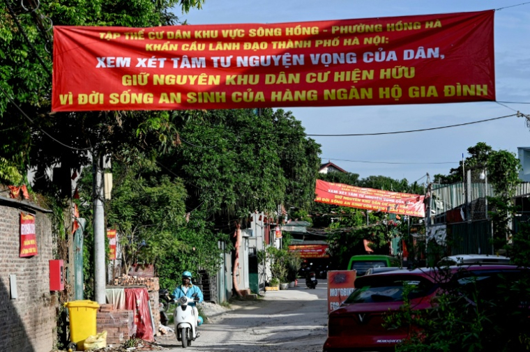Des banderoles de protestation contre un vaste projet de réaménagement suspendues au-dessus d'une rue d'un quartier de Hanoï, le 19 juin 2026 au Vietnam ( AFP / STR )