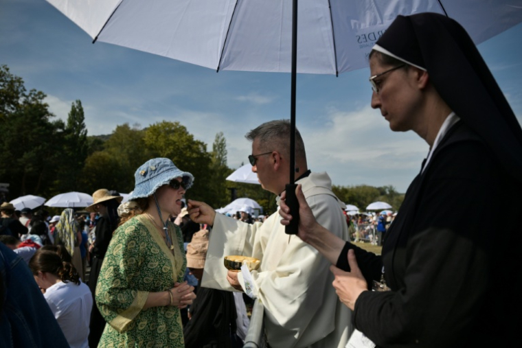 Une fidèle communie sur la prairie du sanctuaire de Lourdes lors de la messe célébrée par le pape Léon XIV, le 27 septembre 2026 ( AFP / Ed JONES )