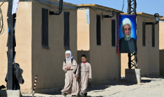 Des filles marchent près d’une affiche du chef du mouvement chiite libanais Hezbollah, Naïm Qassem, sur un préfabriqué du Complexe résidentiel de l'imam Ali, où des Libanais déplacés et des réfugiés syriens chiites résident près de la ville de Hermel, dans le nord-est du Liban, le 4 février 2026 ( AFP / Joseph EID )