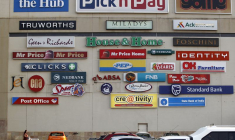 Un client pousse son chariot alors que des logos de magasins sont affichés sur un mur du centre commercial de Lenasia, au sud de Johannesburg