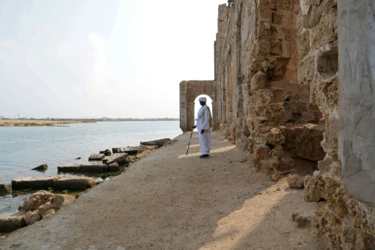 Un homme se tient face à la mer, devant une ruine dans le port soudanais de Suakin, le 22 janvier 2026 ( AFP / Mutawakil ISSA )