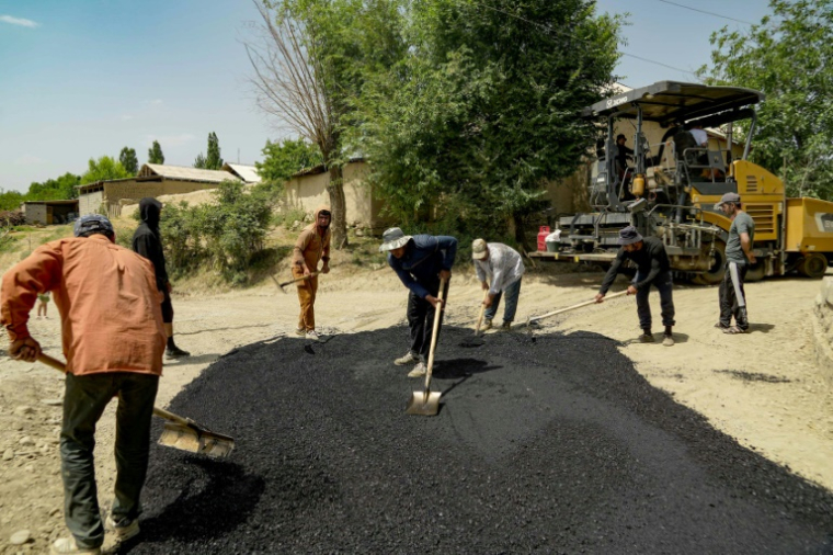 Des ouvriers asphaltent une route dans le village de Mehrobod, un projet de développement financé par des migrants tadjiks à l'étranger, le 25 mai 2025 au Tadjikistan ( AFP / STRINGER )