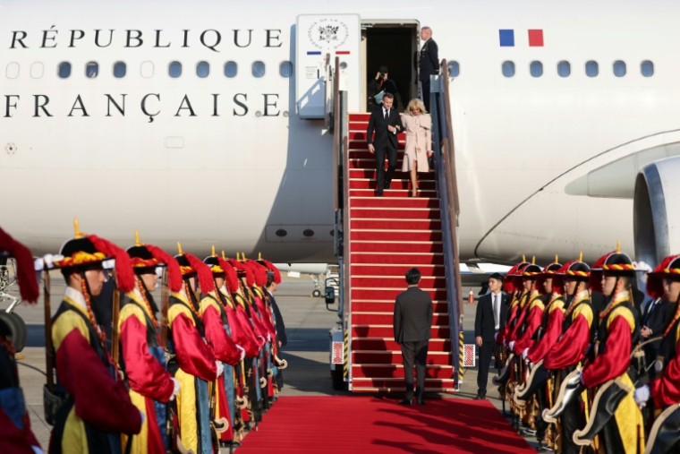 Le président français Emmanuel Macron (G) et son épouse Brigitte Macron (D) arrivent à la base aérienne de Séoul à Seongnam le 2 avril 2026 ( POOL / Ludovic MARIN )