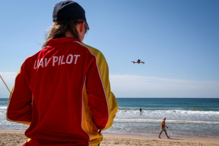 La secouriste Eliza Heys pilote son drone au large d'une plage à Sydney, le 1er octobre 2025 ( AFP / DAVID GRAY )