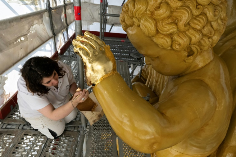 La restauratrice d'art Cyrielle D'Antoni travaille avec des feuilles d'or sur la statue de Jésus, à côté de la Vierge Marie, lors de la rénovation de la basilique Notre-Dame de la Garde à Marseille, le 3 septembre 2025 ( AFP / Miguel MEDINA )
