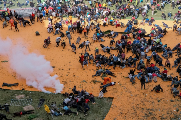 Des partisans et personnes en deuil se mettent à l'abri après que des coups de feu et des gaz lacrymogènes ont été tirés lors d'un rassemblement pour l'exposition publique du cercueil du leader de l'opposition kenyan Raila Odinga au stade Kasarani à Nairobi, le 16 octobre 2025, au lendemain de son décès en Inde ( AFP / KABIR DHANJI )