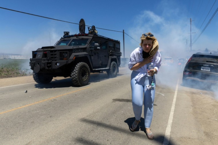 Une manifestante fuit au milieu des gaz lacrymogènes lancés par la police de l'immigration lors d'une descente dans une ferme de Camarillo, en Californie, le 10 juillet 2025 ( AFP / BLAKE FAGAN )