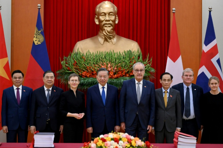 Le président du Vietnam, To Lam (c), la Première ministre du Liechtenstein, Brigitte Haas (3e g), et le président de la Suisse, Guy Parmelin (3e d), aux côtés de délégués lors de la cérémonie de signature de l'accord de libre-échange entre le Vietnam et l'AELE, le 18 octobre 2026 à Hanoï ( AFP / Nhac NGUYEN )