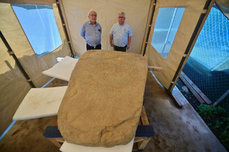 Les archéologues Lino Espinoza (g) et Alberto Vazquez (d) près d'une stèle de 2,5 tonnes découverte sur un site archéologique à Coatepec, au Mexique, le 18 juin 2026 ( AFP / Marco Antonio MARTINEZ )