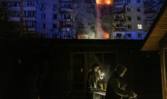 Des gens passent devant des magasins endommagés près d'un immeuble résidentiel en feu à la suite d'une attaque de drones russes sur la ville de Vychhorod, dans la banlieue de Kiev, tôt le matin du 30 novembre 2025 ( AFP / Roman PILIPEY )