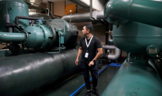 Un technicien de la société Recoolit travaille à capturer les gaz de refroidissemen d'une grande unité de climatisation au sous-sol d'un complexe d'habitation à Jakarta, le 10 juin 2025 en Indonésie  ( AFP / Jack Moore )