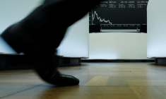 Un trader passe devant le graphique de l'indice des prix des actions allemandes DAX à la bourse de Francfort