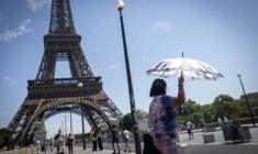 Une touriste se protège du soleil sous un parapluie, le 10 juillet 2026 à Paris  ( AFP / Behrouz MEHRI )